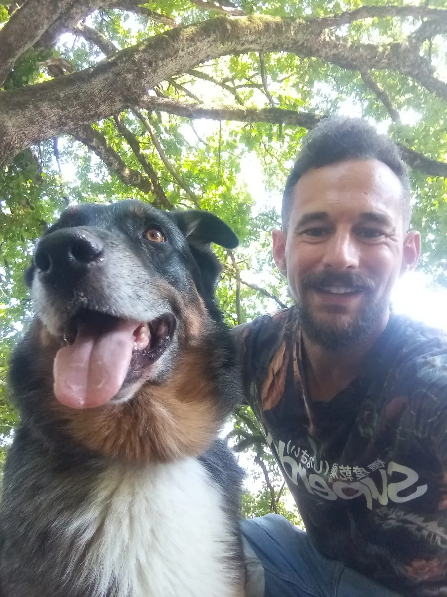 Un pet-sitter avec un chien tricolore sous les arbres